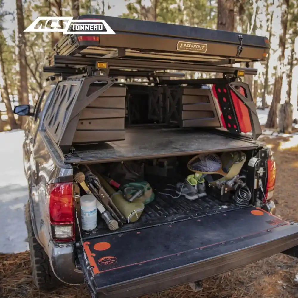 Tacoma Truck bed with open toolbox and tools, surrounded by trees.