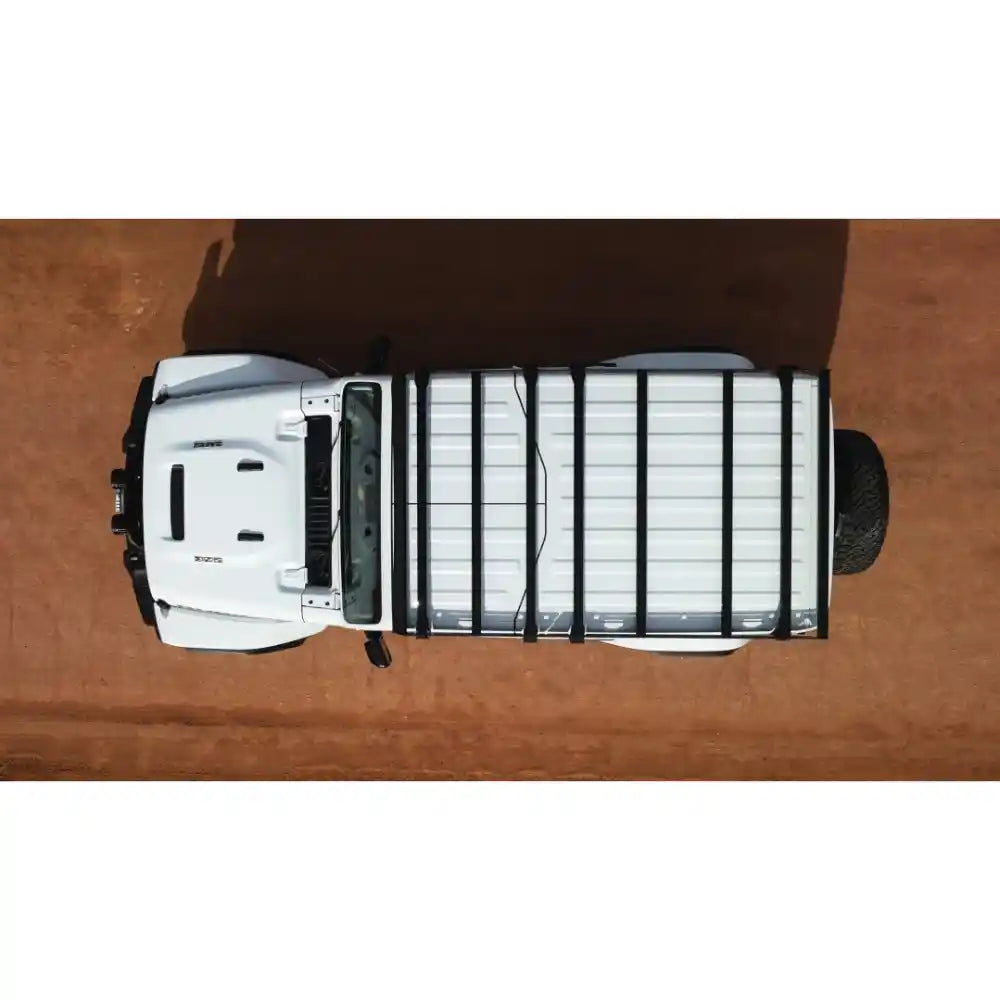 Top-down view of a white JLU with a black Sherpa Starlight roof rack on a wooden surface