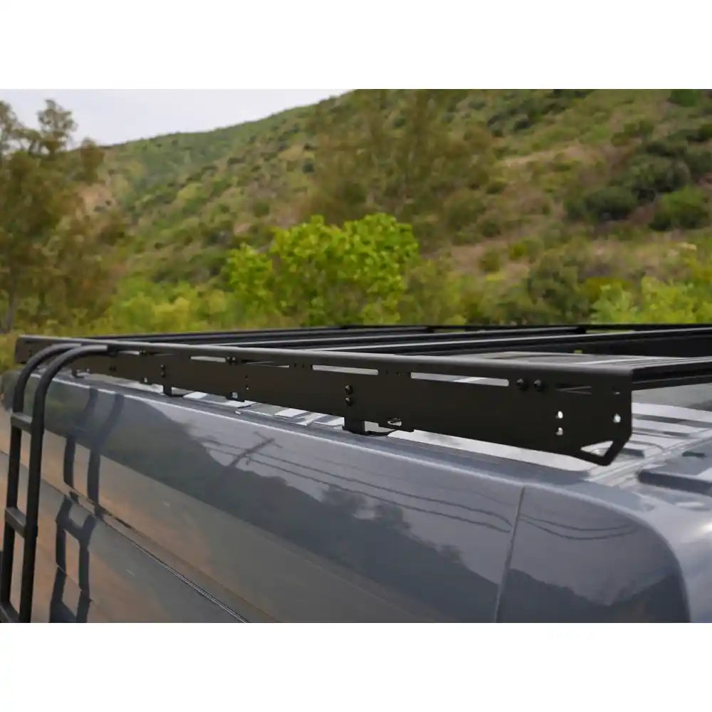 Transit roof rack mounted with a scenic background of trees and hills.