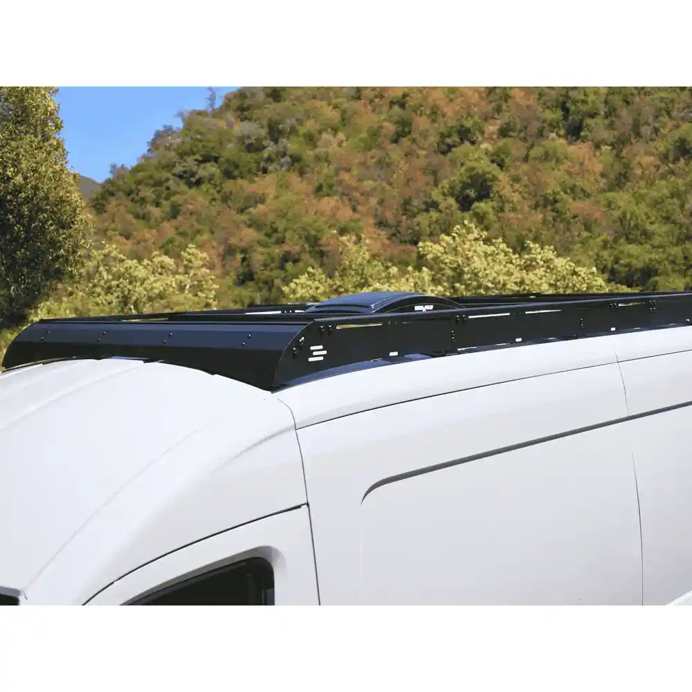 Transit roof rack system with a scenic background of trees and blue sky.