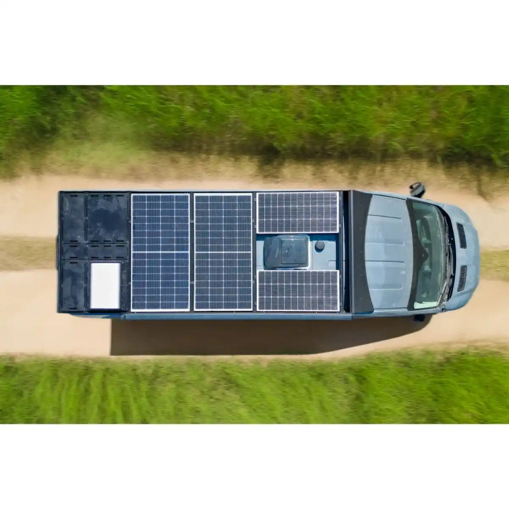 Top-down view of a Transit with solar panels on its roof in a natural setting.