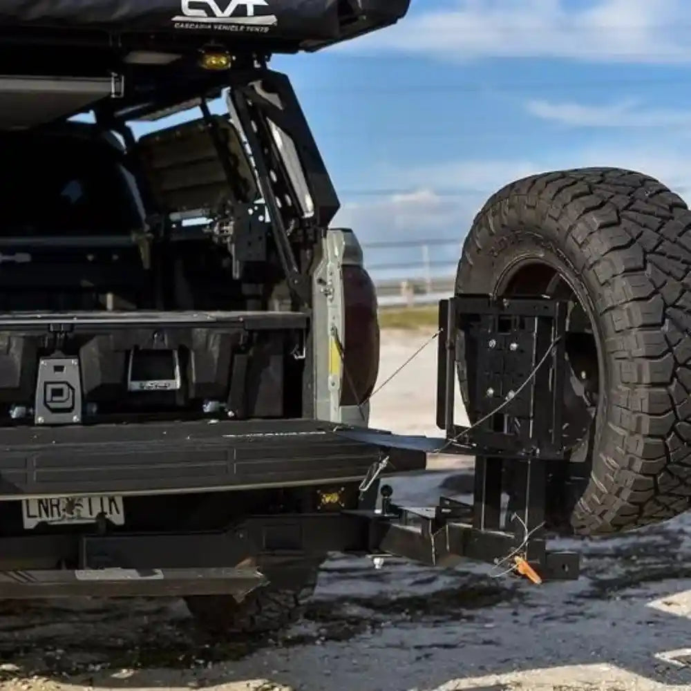 Tundra with a Rigid Armor Swing out Tire Carrier attached on a road with a clear sky.