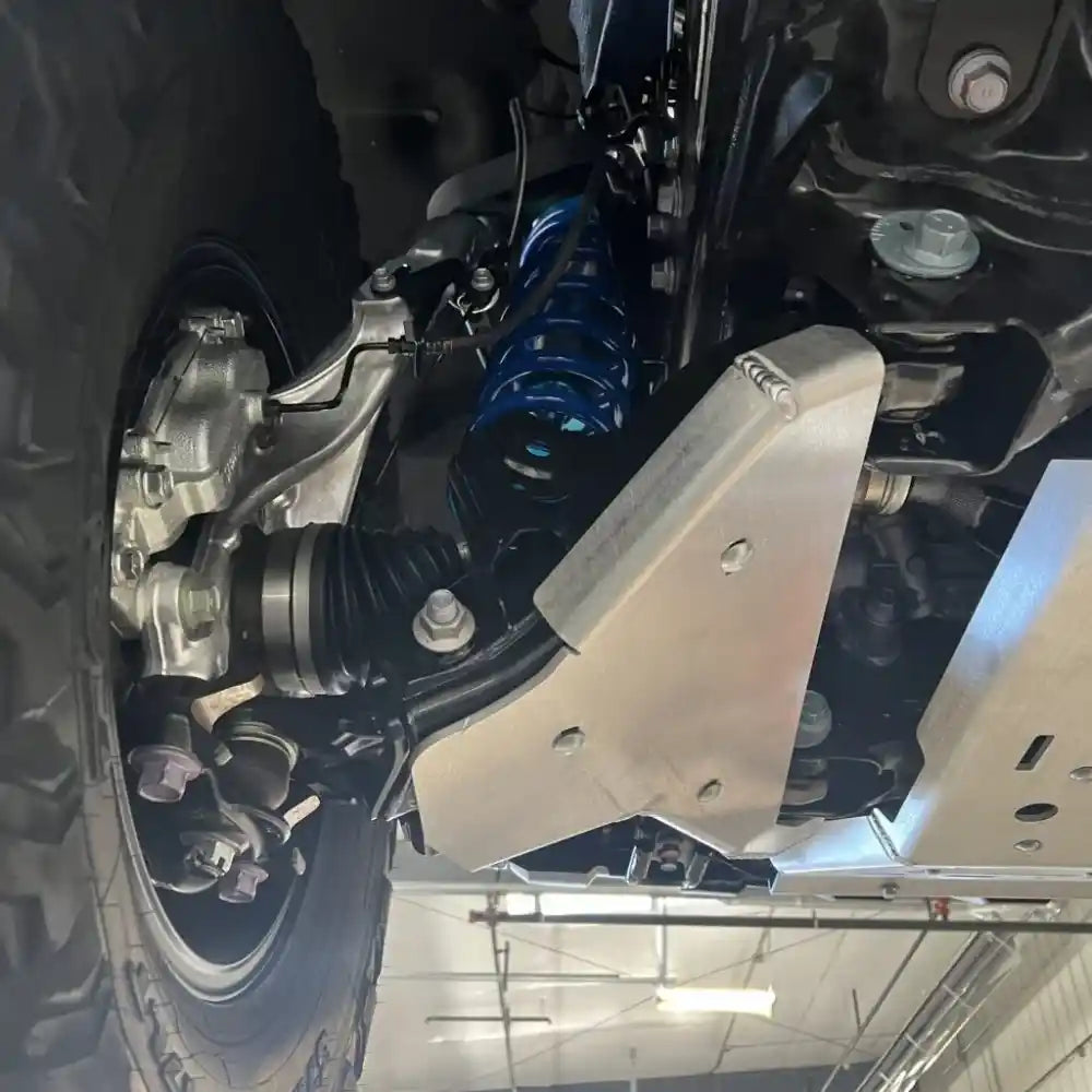 Under-vehicle view of silver RCI A-arm skids covering front suspension