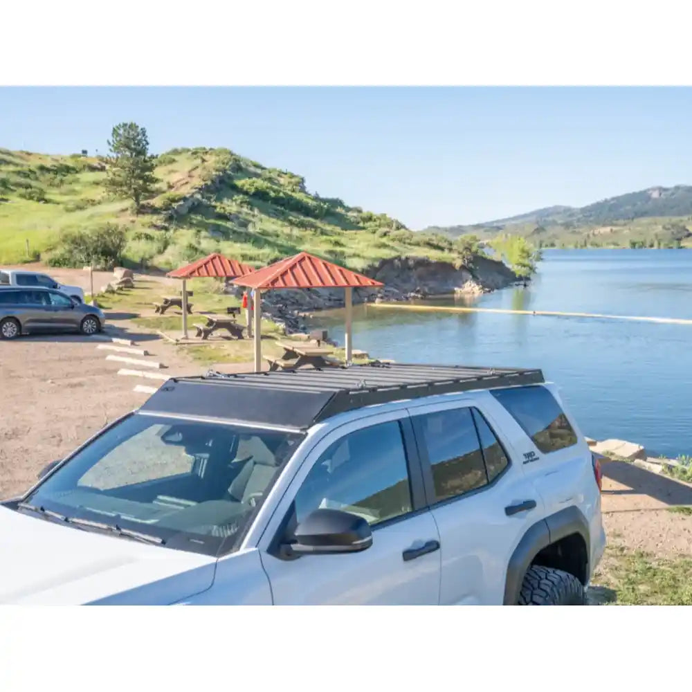 White 4Runner in wooded clearing with low-profile RCI full-length rack installed