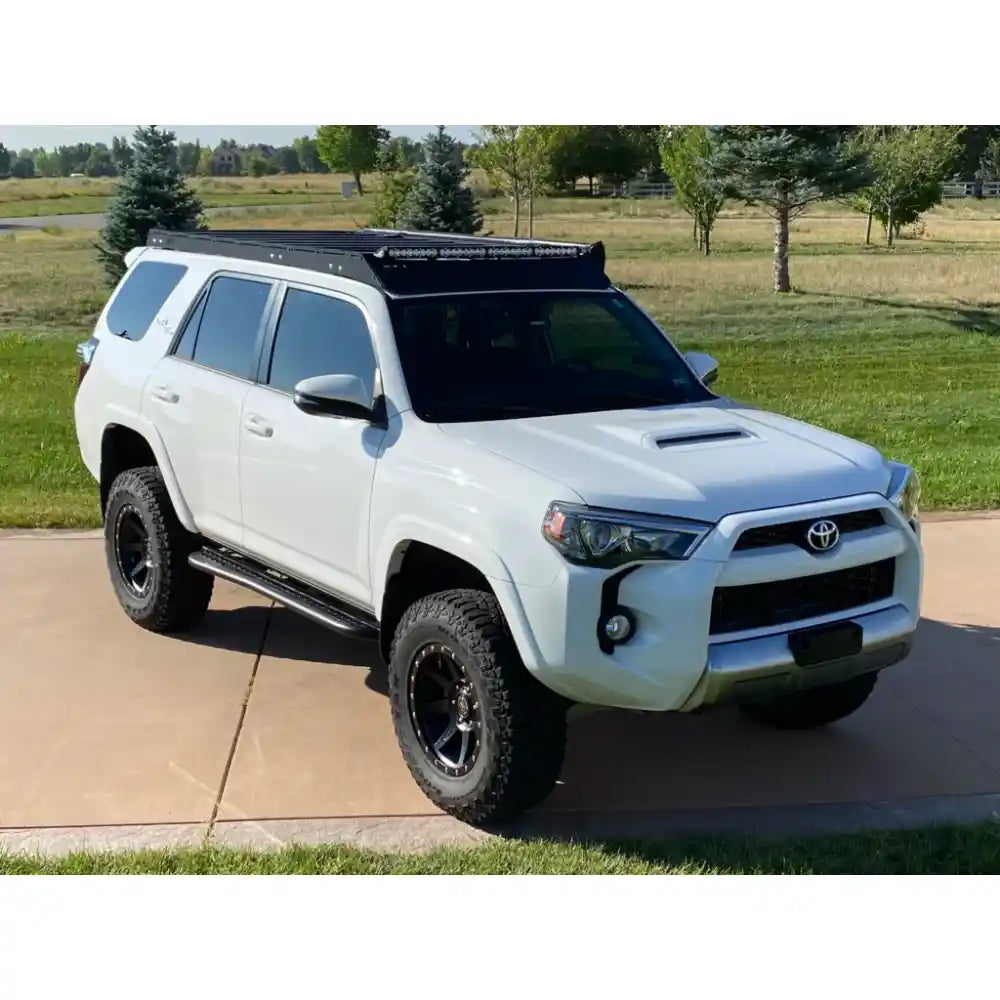 White 4Runner on rocky path with secure RCI roof rack and dramatic rock formations