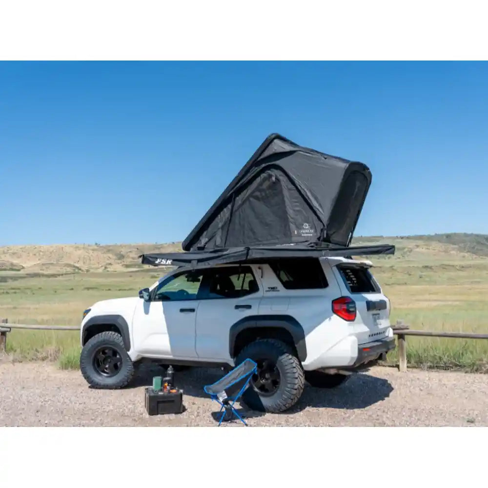 White 4Runner with popped-up rooftop tent perched on RCI rack in wide-open sunny grassland
