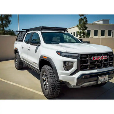 White GMC truck with roof rack on a clear day