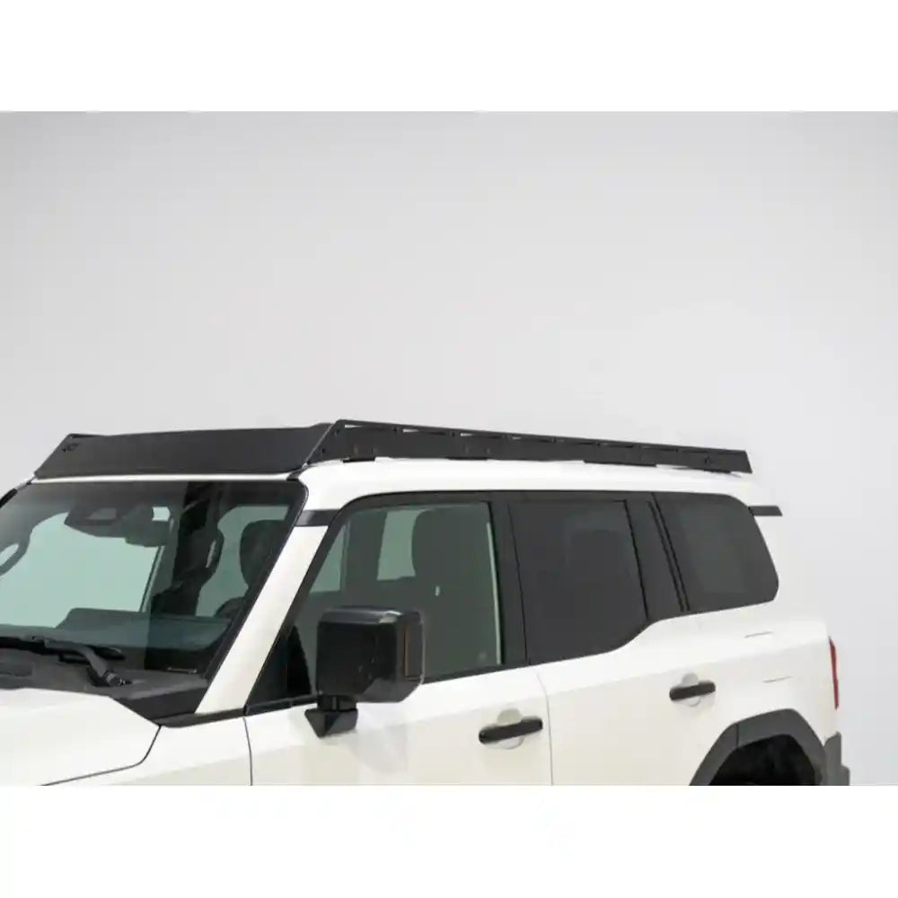 White Land Cruiser 2024+ parked in bright indoor space with sleek black RCI full-length roof rack installed