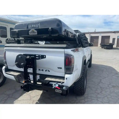 White Tacoma with installed tire carrier in a parking lot