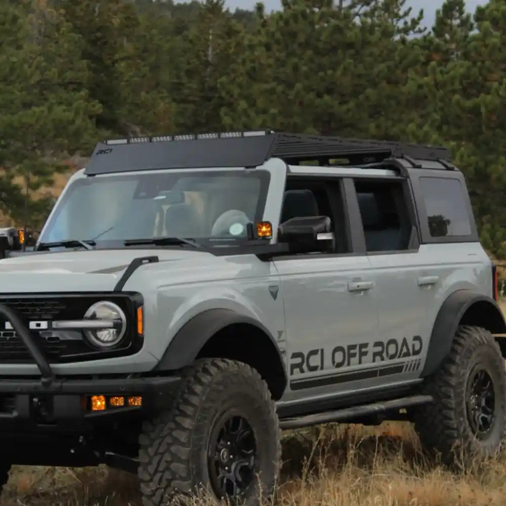 White off-road Bronco with RCI Off Road roof rack in a forested area