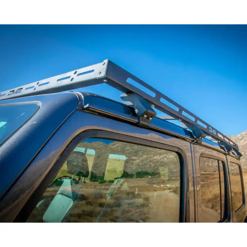 Close-up side view of the DV8 Offroad Roof Rack mounted on a blue Jeep Wrangler JL 4-Door