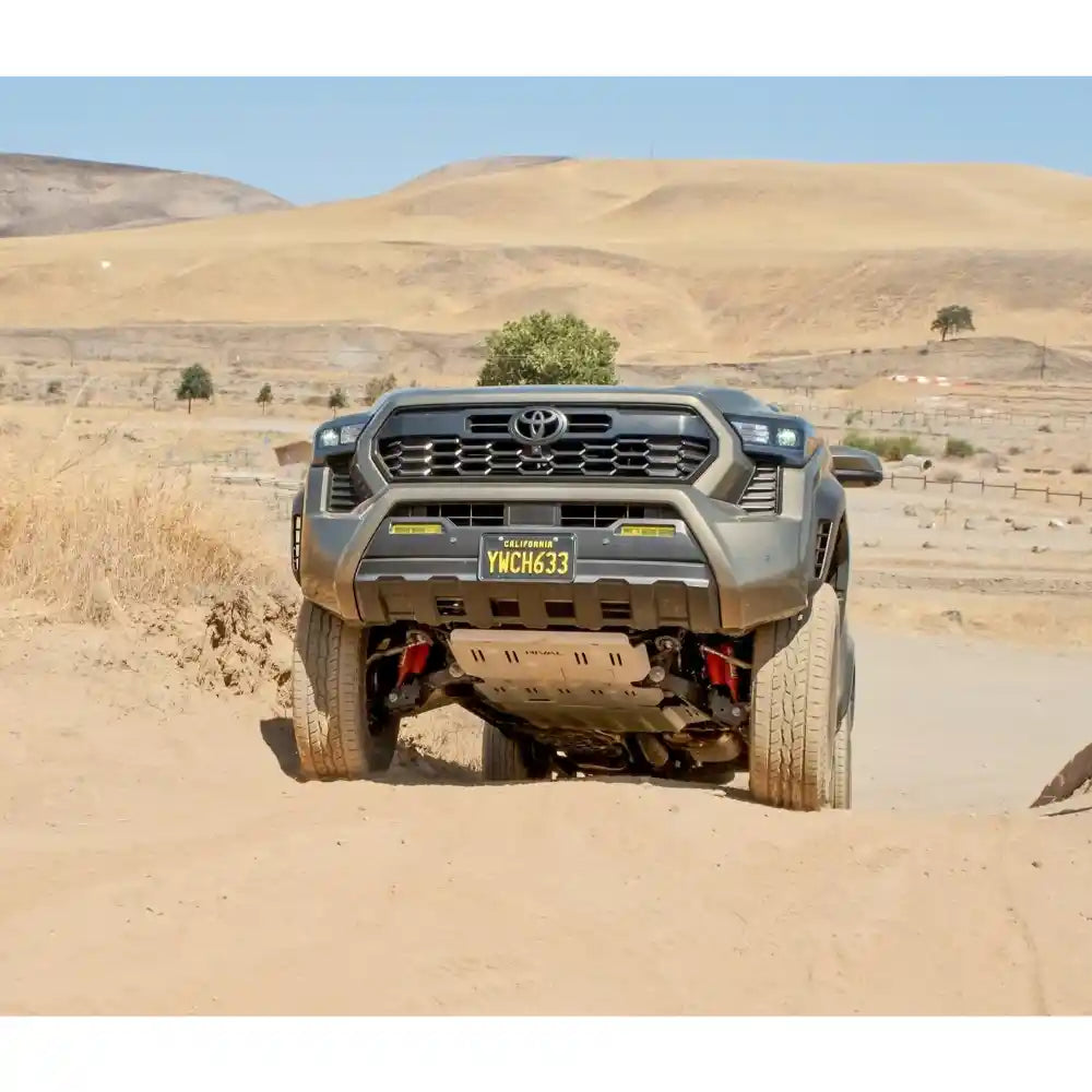 4Runner driving on a sandy terrain with mounted engine skid plate with mountains in the background