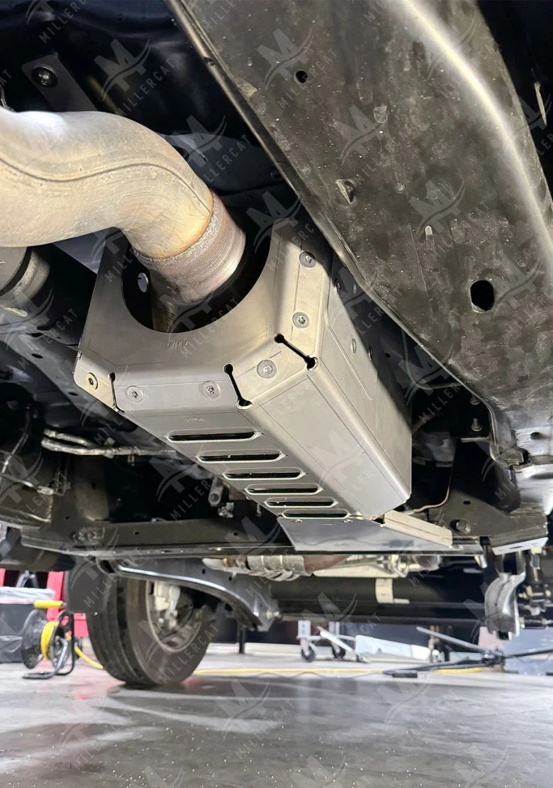 Close-up of a vehicle's undercarriage with a CAT protective guard and exhaust system.