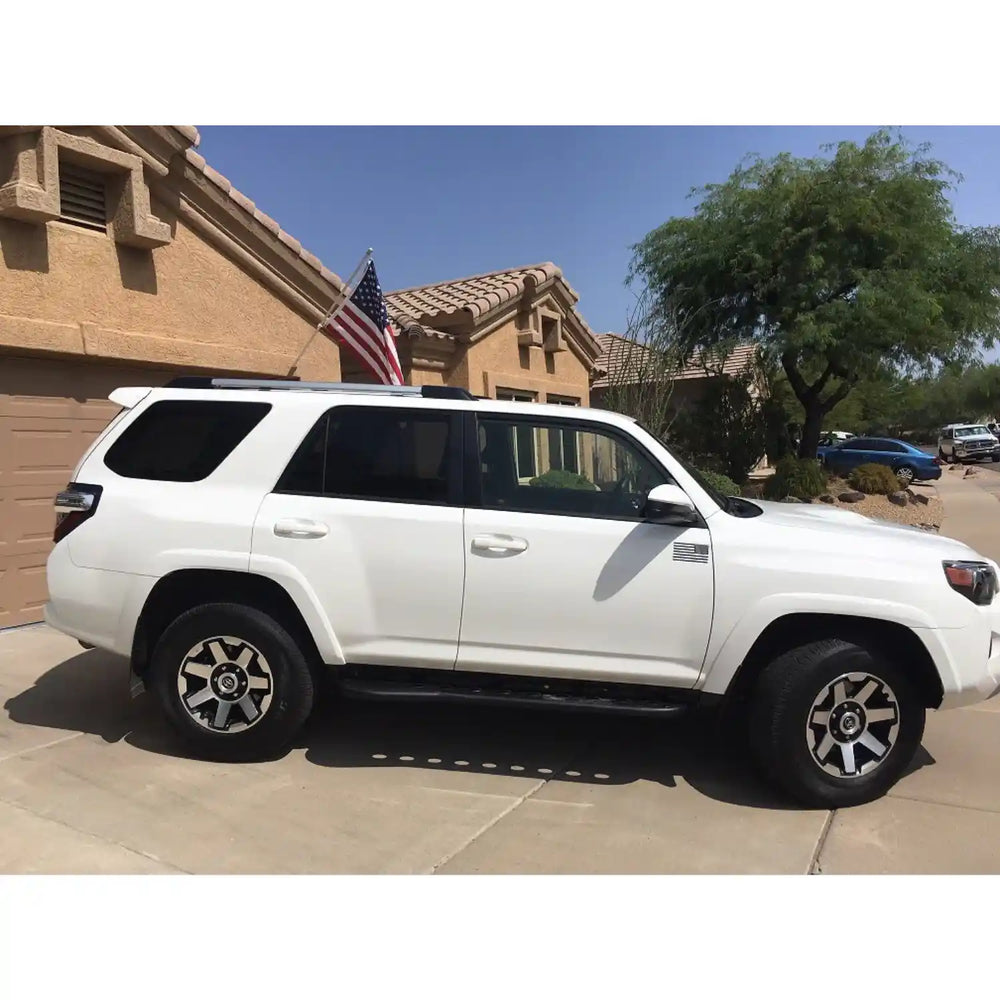 Side of of Installed Rock Sliders on White SUV parked in a driveway with a house and American flag in the background