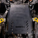 Front three-quarter underbody view of the transmission skid plate installed between the 4Runner's front suspension arms, showing mounting bolts