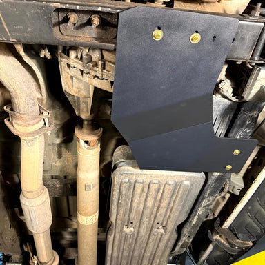 Close-up of the Juggernaut transfer case skid plate mounted near the crossmember of a 2009-2014 Ford F-150