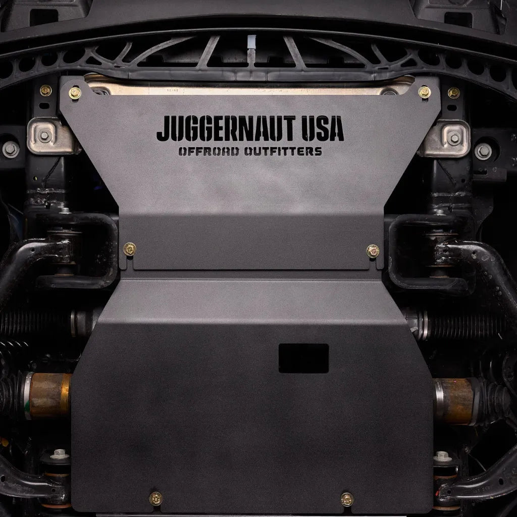 Juggernaut Ford F-150 engine skid plate installed, straight-on underbody view showing the embossed JUGGERNAUT USA logo behind the front bumper