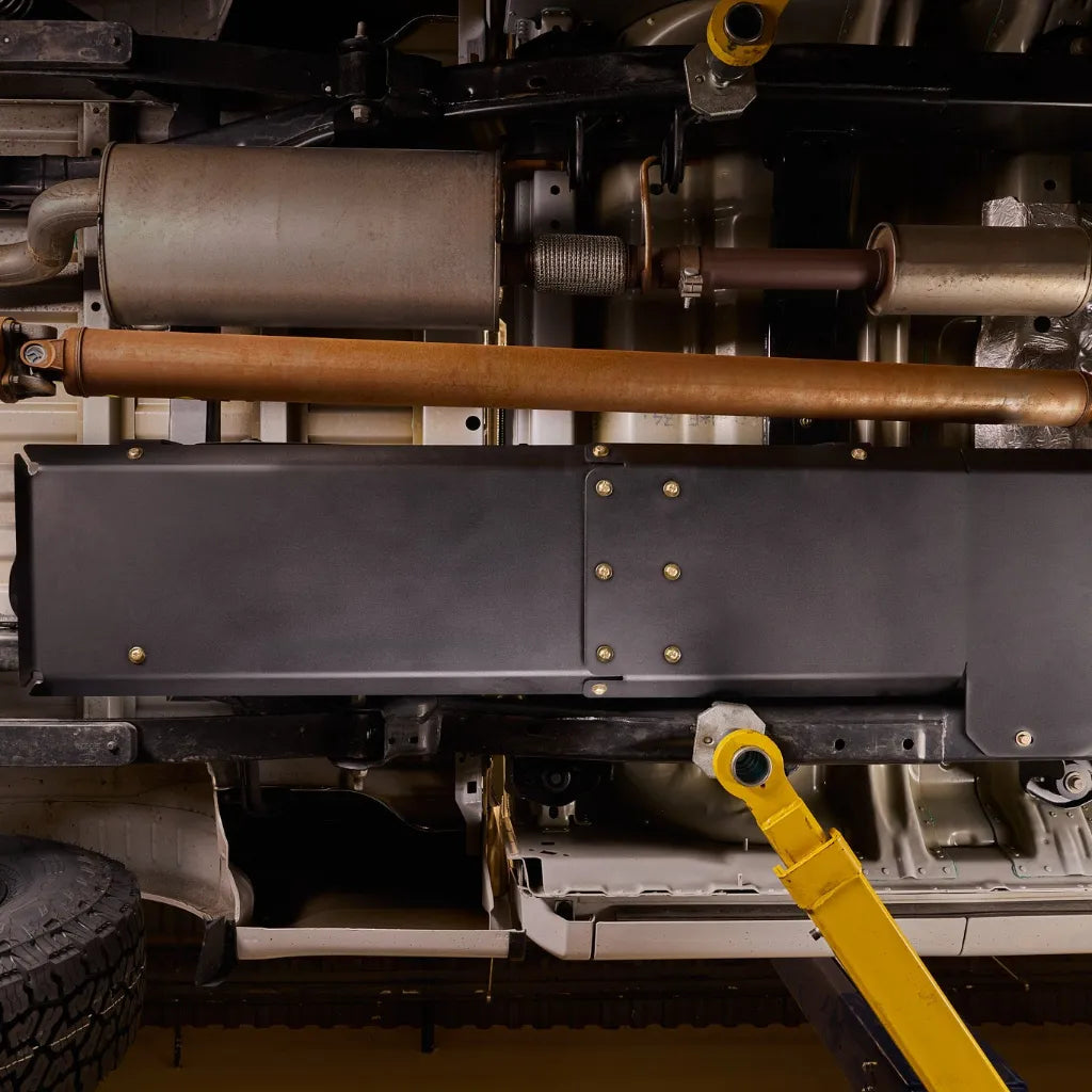 Close-up of the Juggernaut gas tank skid plate mounted to the F-150 frame rail near the gas tank