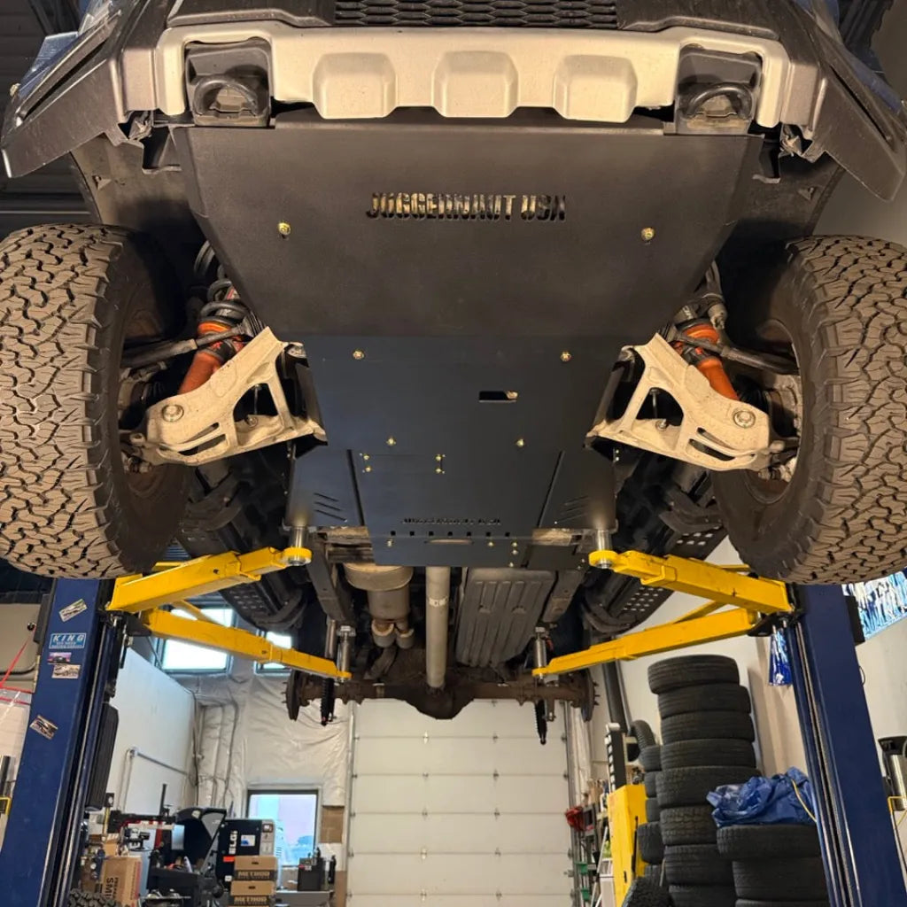 Juggernaut Raptor skid plate package mid-section installed, covering the transmission and exhaust run