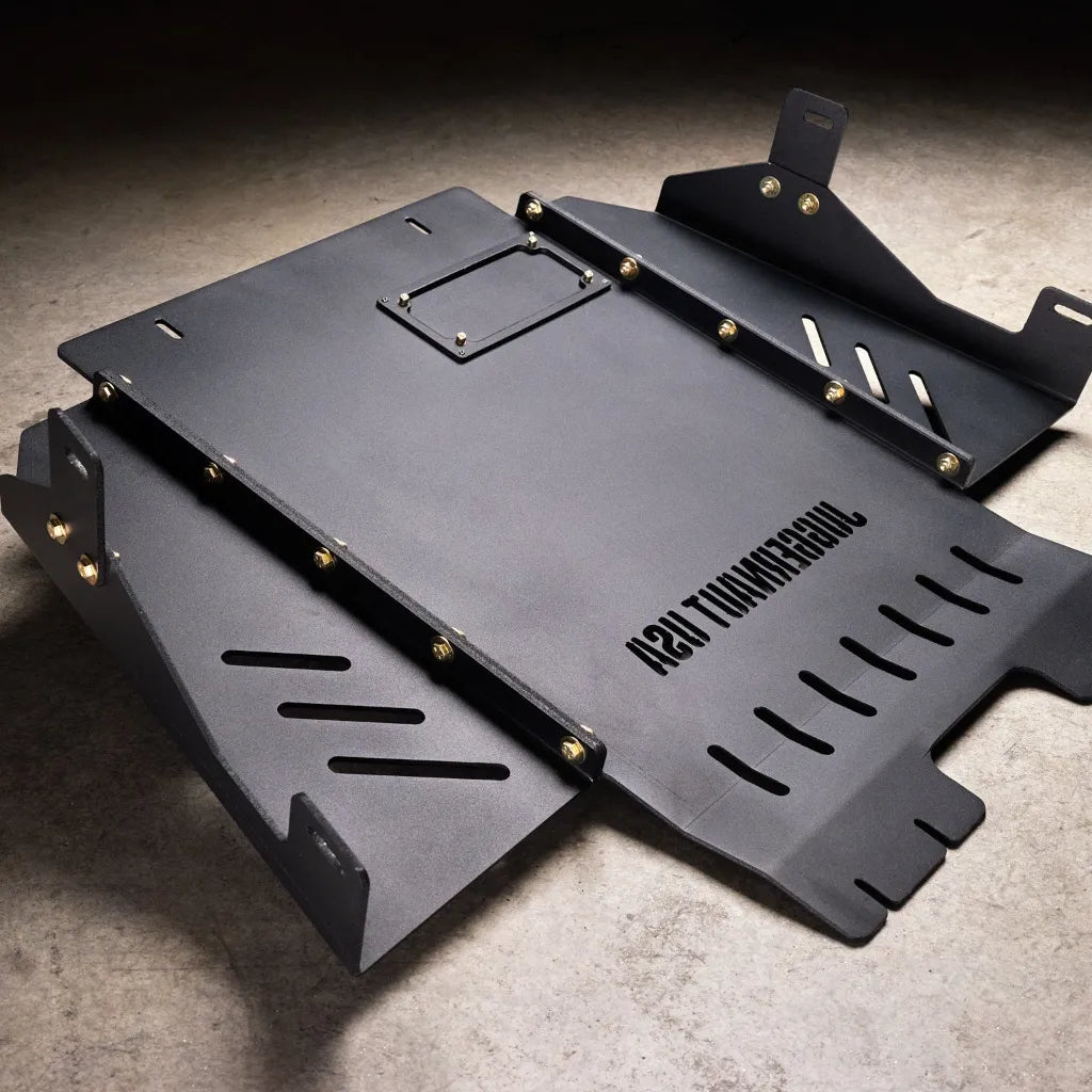 Juggernaut Ford F-150 Raptor transmission skid plate, second angle showing the powder-coated black finish and oil-drain cutout