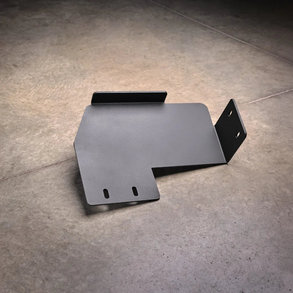 Standalone Ford F-150 transfer case skid plate product view on shop floor, showing the angled bracket shape