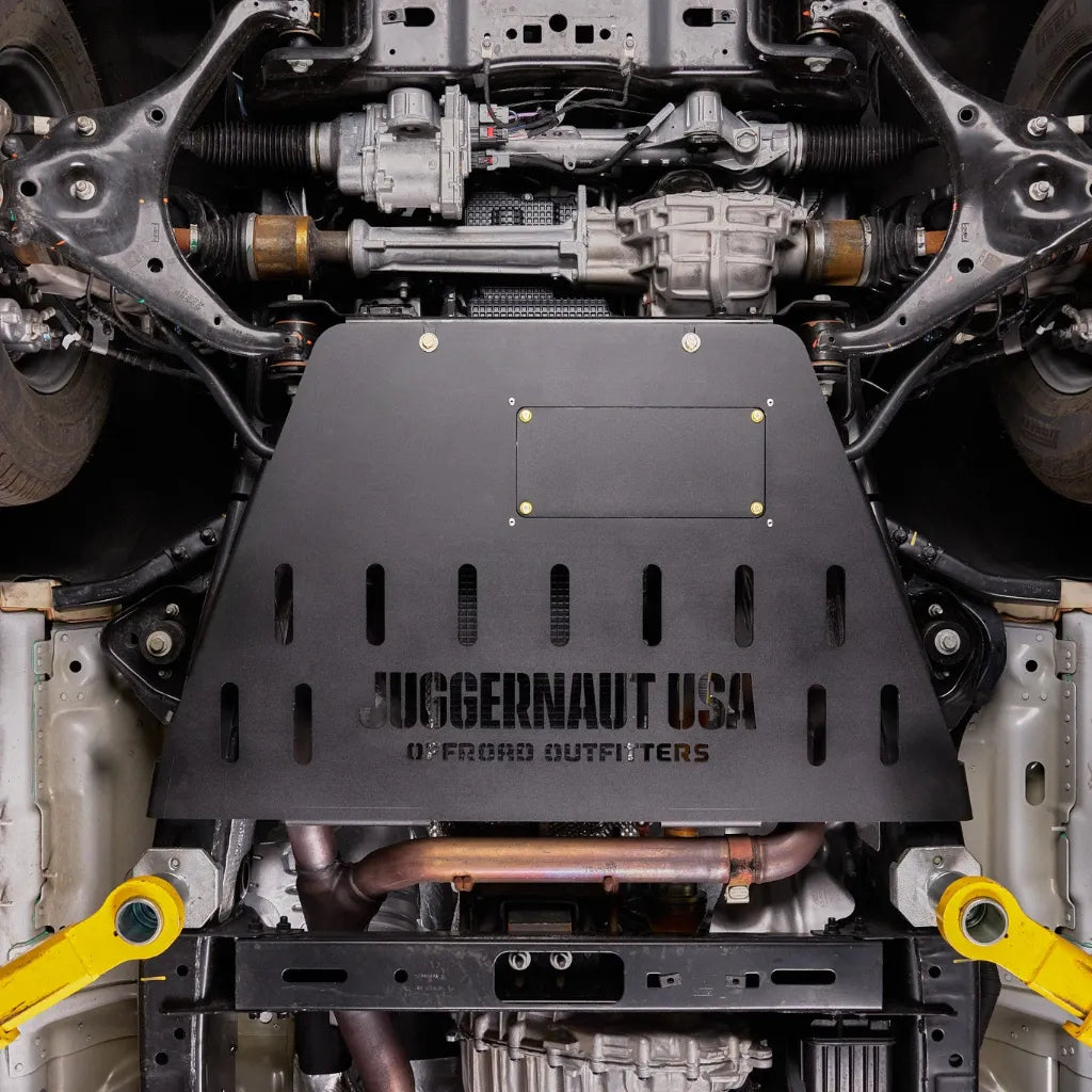 Juggernaut Ford F-150 transmission skid plate installed, wide underbody view showing the front differential and CV axles