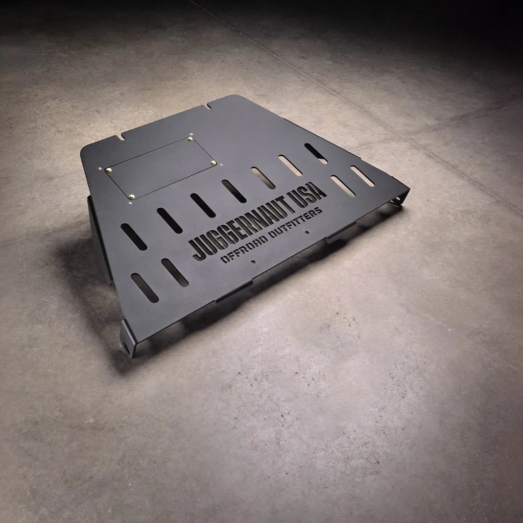 Standalone Ford F-150 transmission skid plate product view on shop floor, showing slotted vents and the oil drain cutout