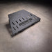 Standalone Ford F-150 transmission skid plate product view on shop floor, showing slotted vents and the oil drain cutout