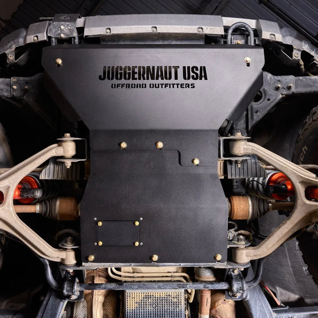 Close-up underbody view of the Juggernaut engine skid plate oil drain access panel