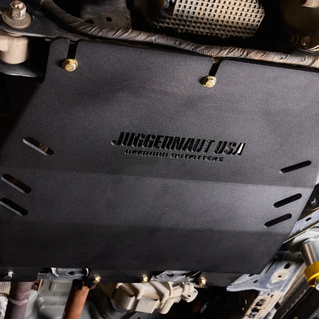 Close-up underbody view of the Juggernaut transmission skid plate covering the catalytic converters