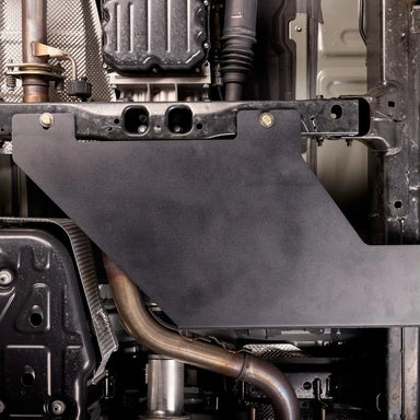 Underbody view of the transfer case skid plate mounted near the exhaust pipe and transmission tunnel