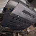 Close-up of the Juggernaut Ford Transit engine skid plate showing the oil drain access panel