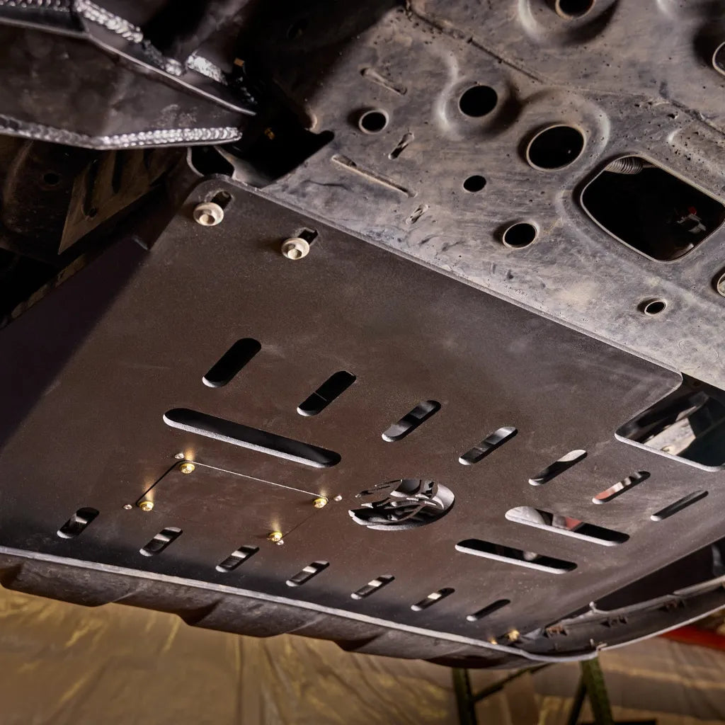 Ford Transit parked on a trail, underbody view showing the Juggernaut skid plate