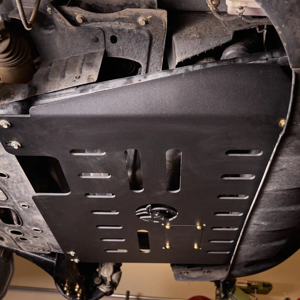 Ford Transit on a trail, angled underbody view of the Juggernaut engine skid plate