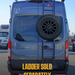 Juggernaut spare tire rack mounted on a Prime Design ladder on the rear door of a Ford Transit
