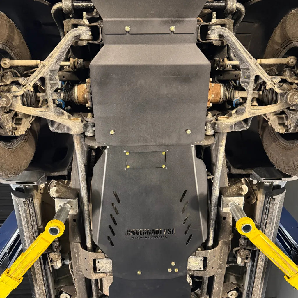 Straight-on view of the Juggernaut USA engine skid plate on a Silverado HD, centered between the front differential and CV axles