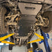 Front-quarter underbody view of the complete Juggernaut USA Silverado HD skid plate package on a shop lift, both front wheels visible