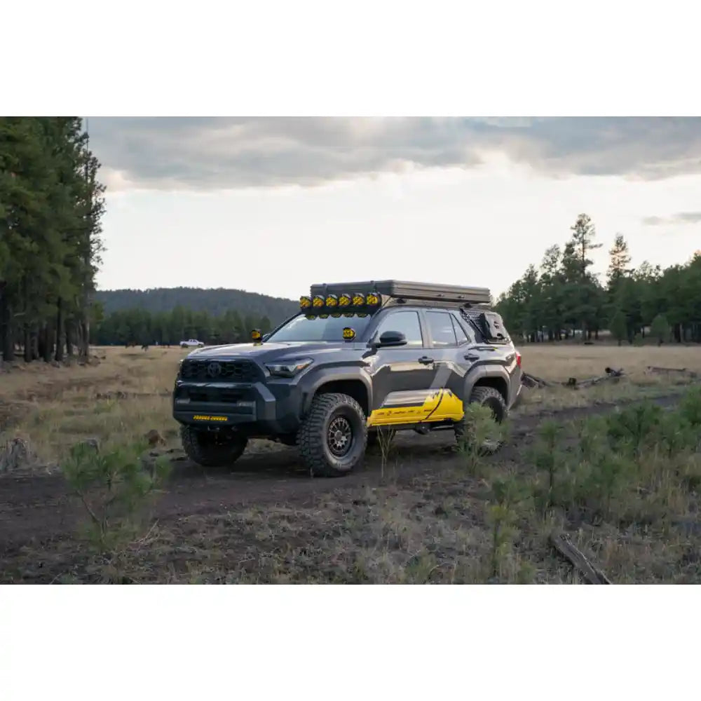 Toyota 4Runner with rooftop tent on Rago roof rack, front three-quarter in forest