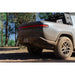 Rivian R1T with Rago chase rack in forest, rear three-quarter