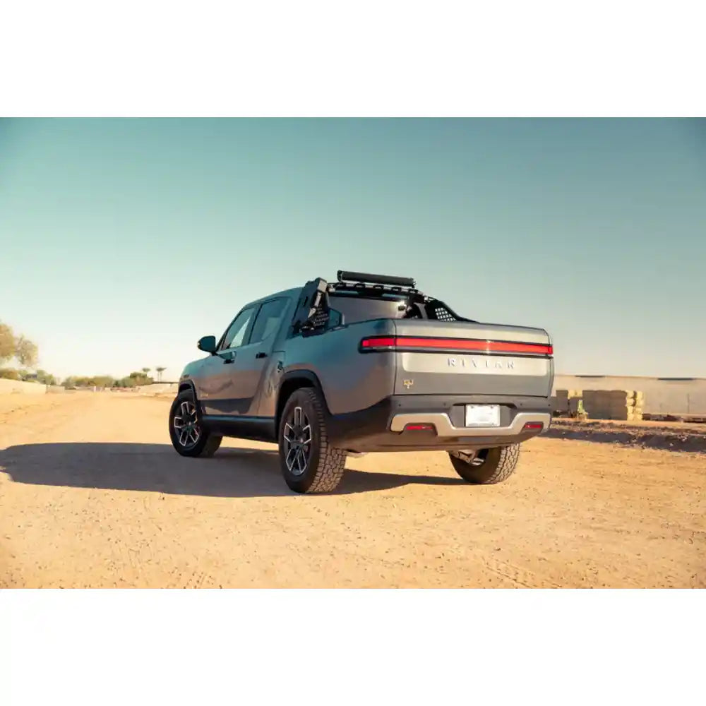 Rivian R1T with Rago chase rack in desert, rear three-quarter