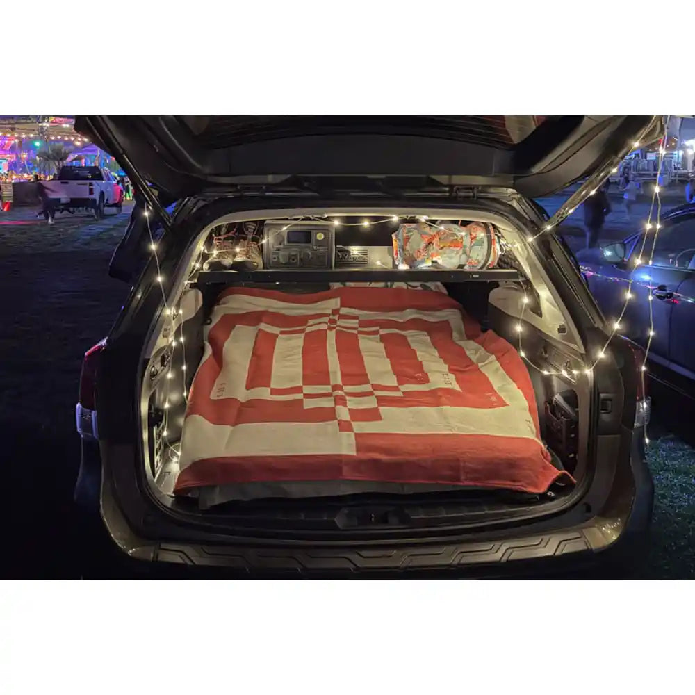 Rago Molle shelf over sleeping setup in Subaru Forester cargo area at night