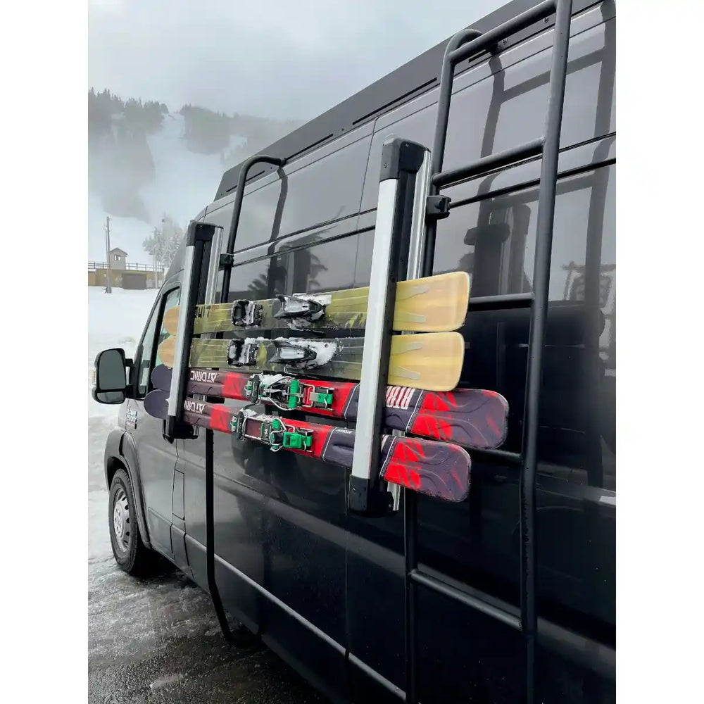 Van with skis attached to the side, snowy landscape in the background