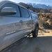 Tacoma truck with rock sliders parked in a desert landscape with mountains in the background