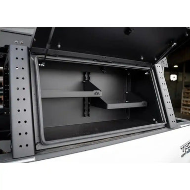 Open storage compartment with metal frame and black interior, showing 'backwoods' branding.