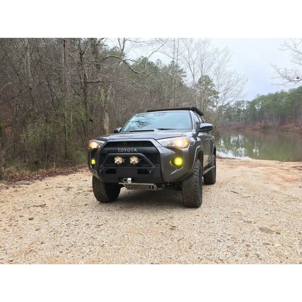 4Runner on a gravel road with trees and water in the background